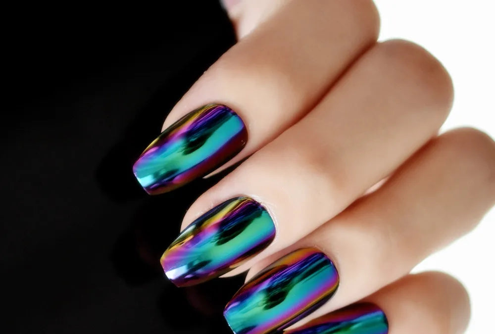 Hand with multicolored metallic nail design on a black background