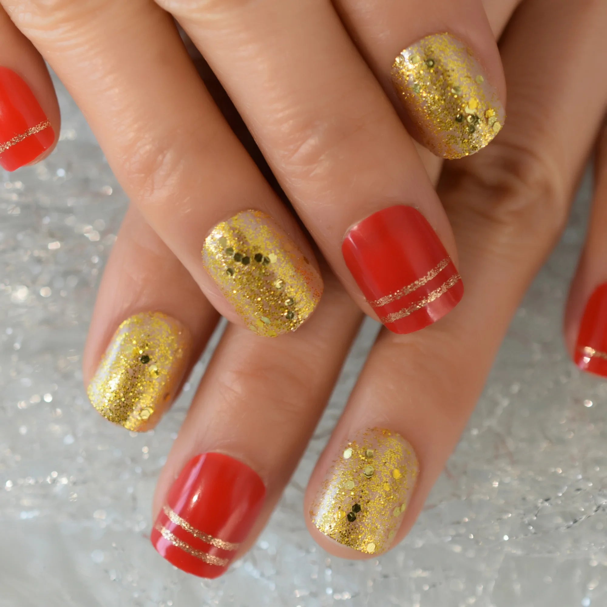 Nails with red and gold glitter design on a glittery background