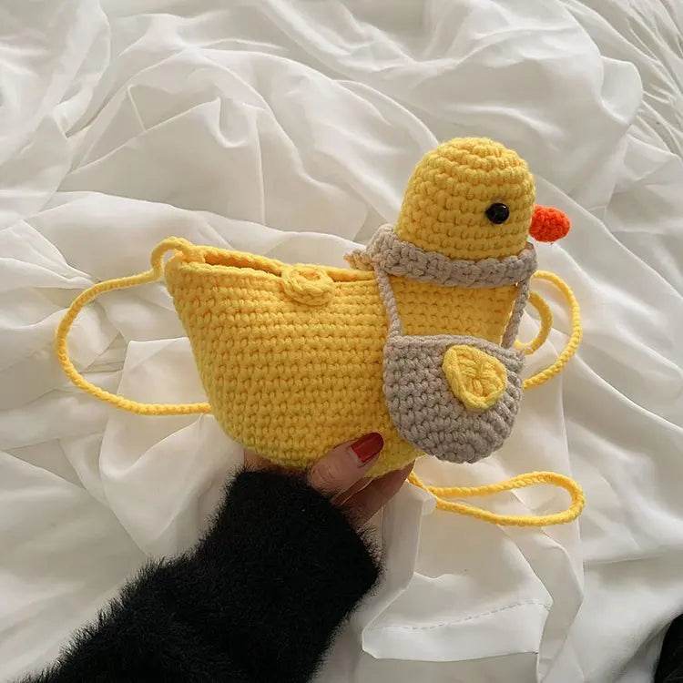 A woman wearing the knitted duck-shaped crossbody bag, showing how it looks when worn.