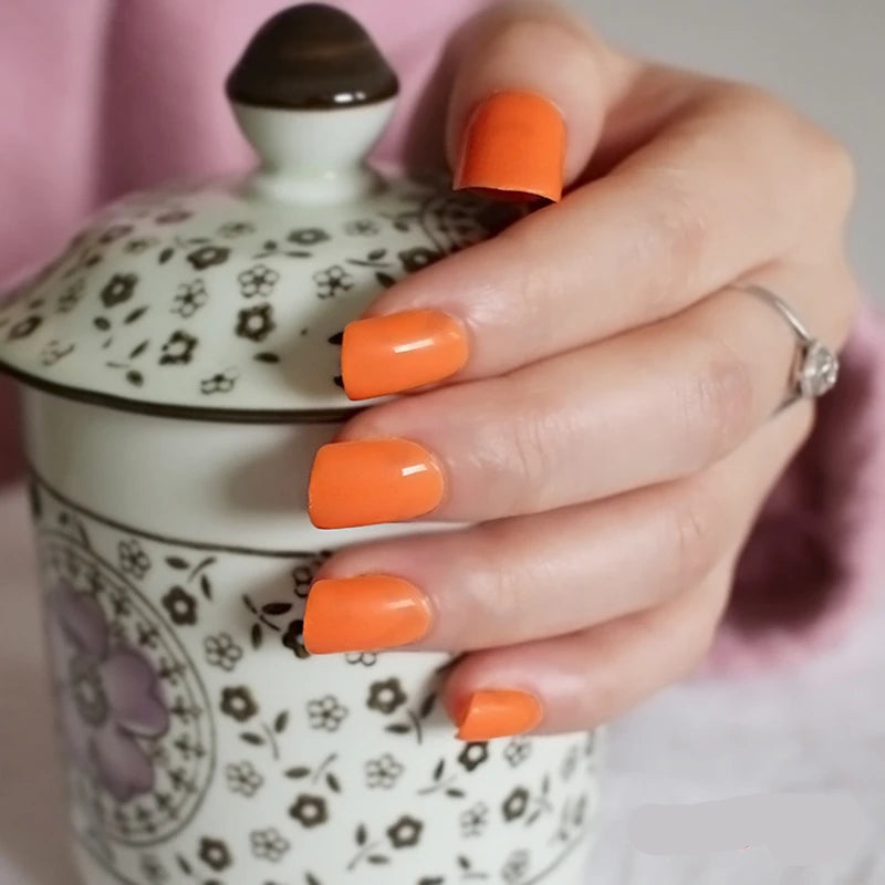 Hand with bright orange nails holding a patterned ceramic jar.