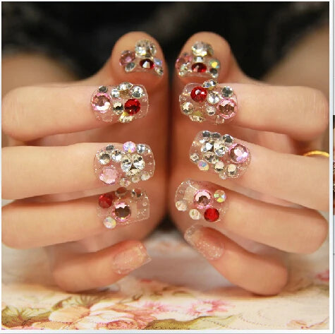 Nails with decorative gemstones held by a person