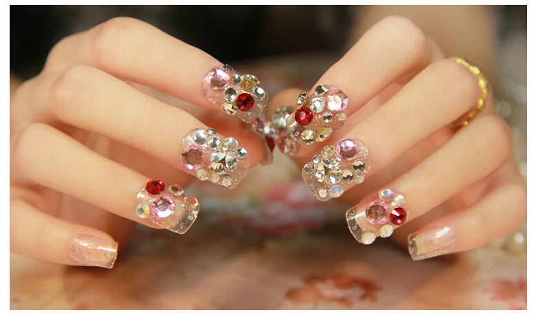 Close-up of a hand with decorative nail art featuring crystals and rhinestones.