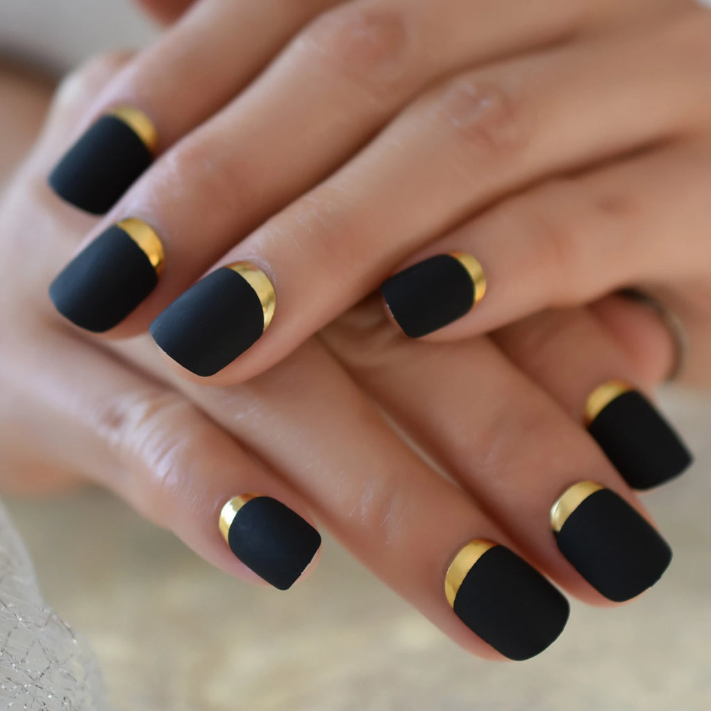Close-up of hands with black nails and gold accents on a neutral background