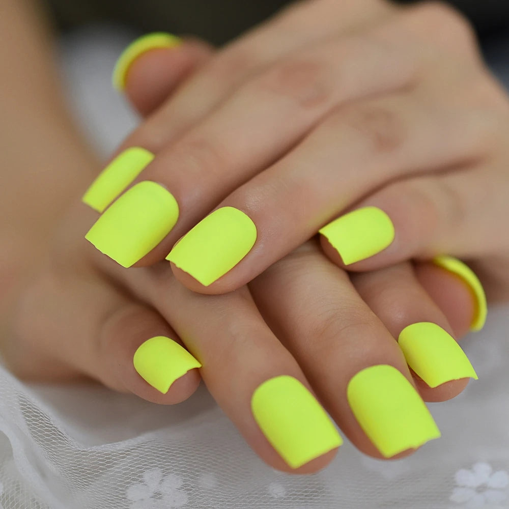 Close-up of hands with neon yellow nail polish on a neutral background