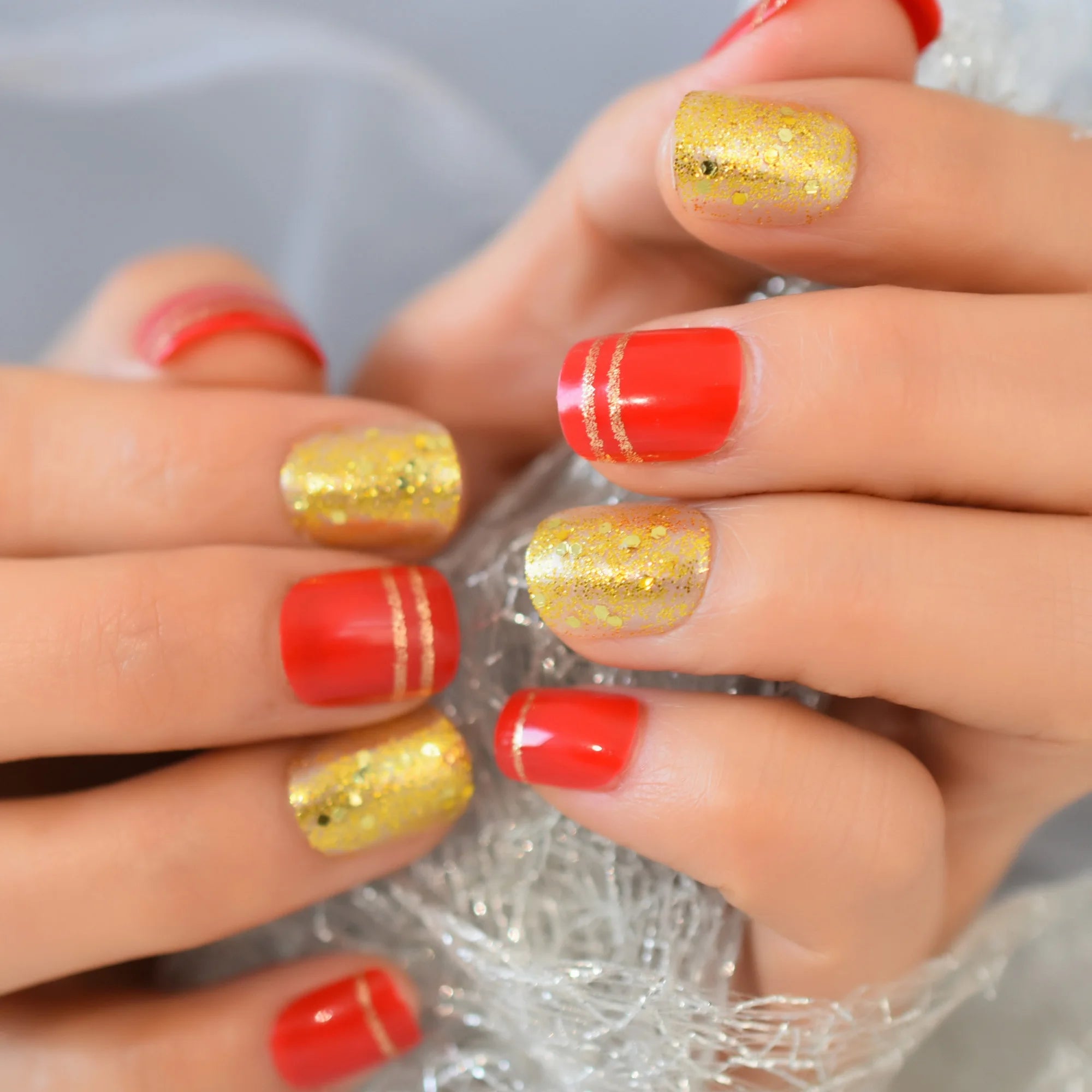 Close-up of hands with red and gold glittery nail polish.