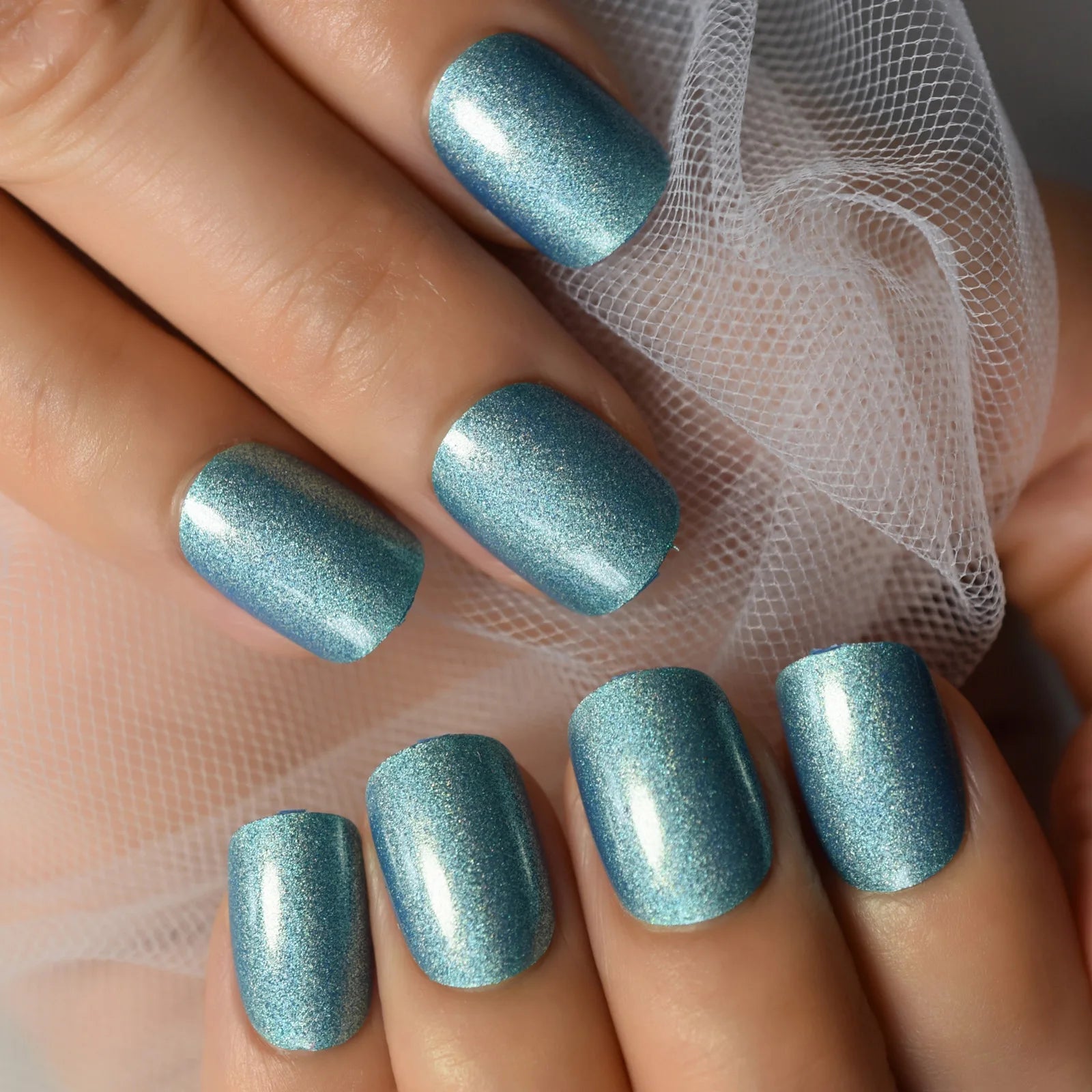 Close-up of a hand with blue glittery nail polish on a neutral background
