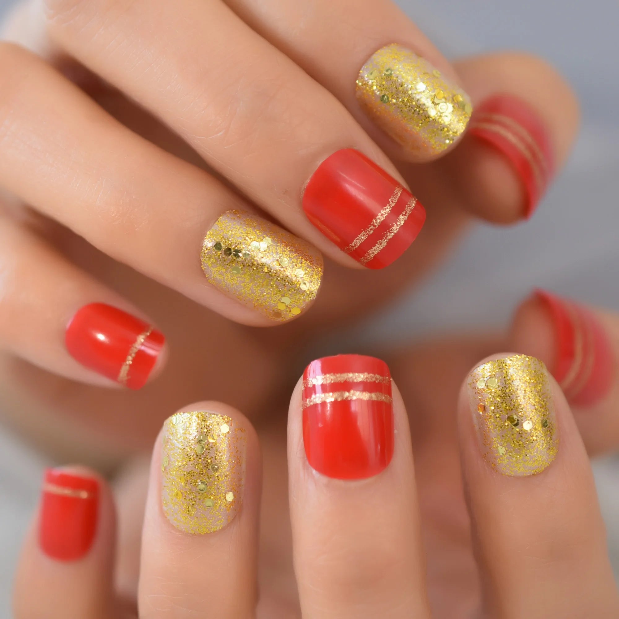 Close-up of hands with red and gold glitter nail polish