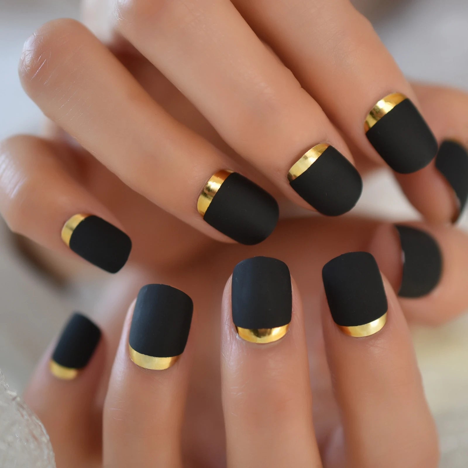 Black nails with gold accents on a hand
