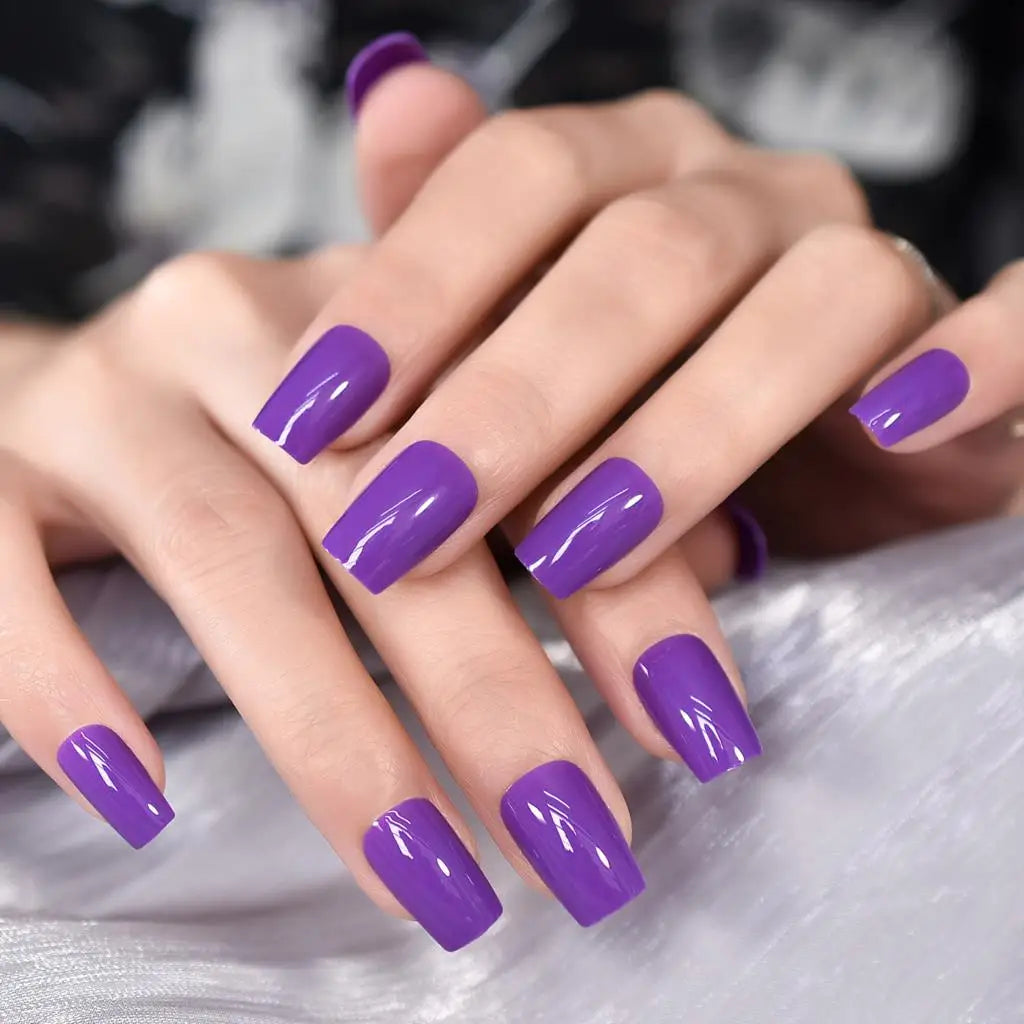 Close-up of hands with purple nail polish on a neutral background