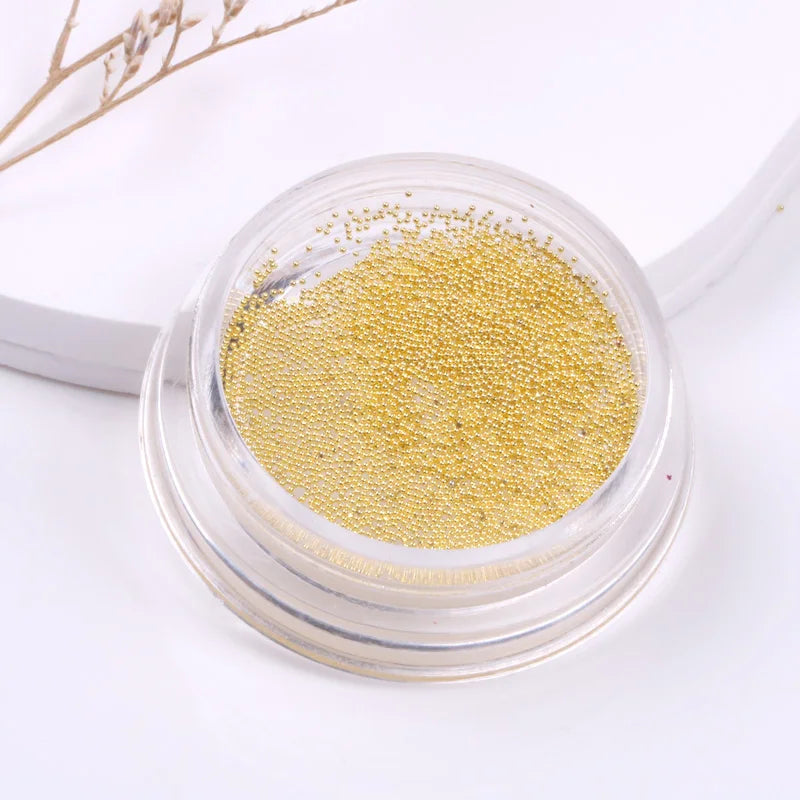 Small container of gold glitter on a white background