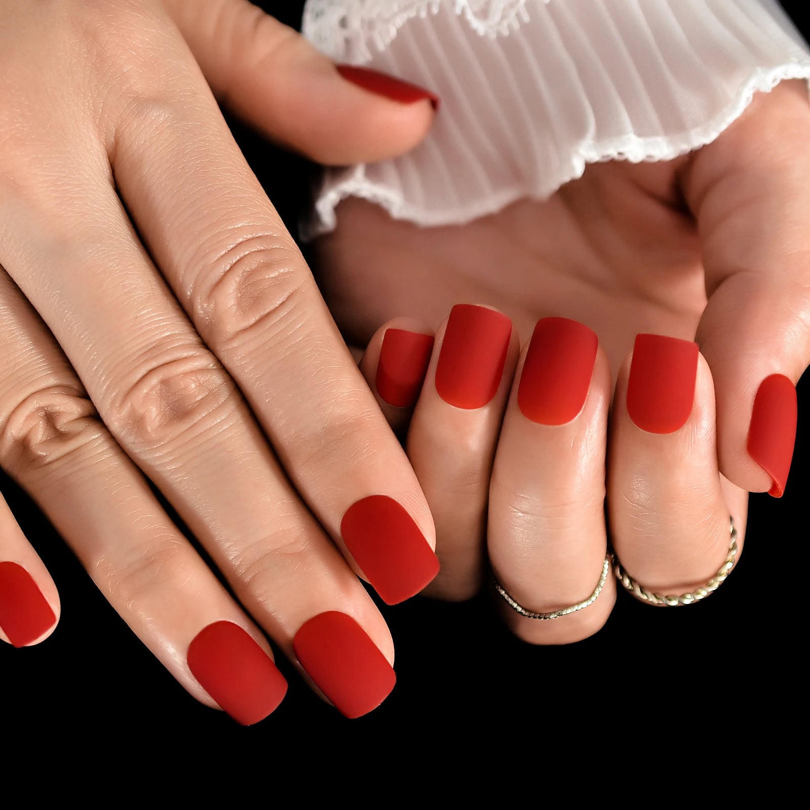 Close-up of hands with red nail polish on a black background