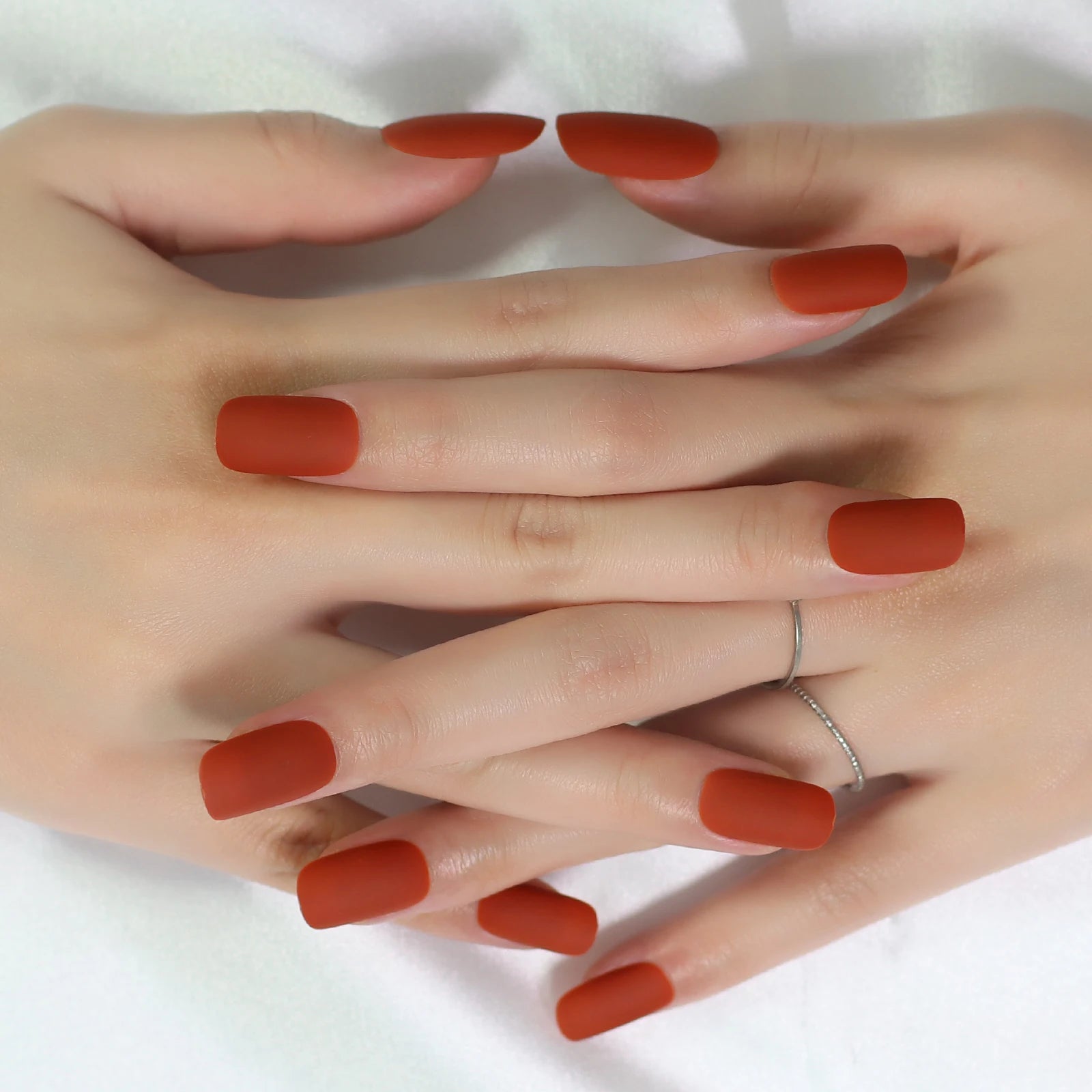 Close-up of hands with red nail polish on a white background