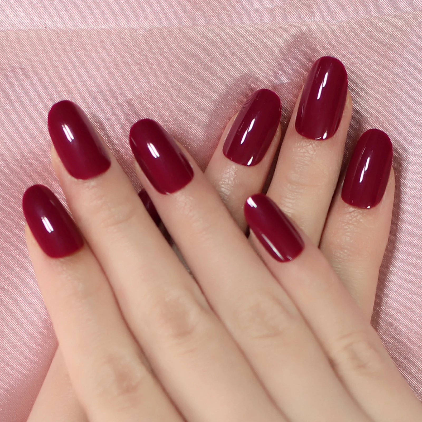 Close-up of a hand with red nail polish on a pink background