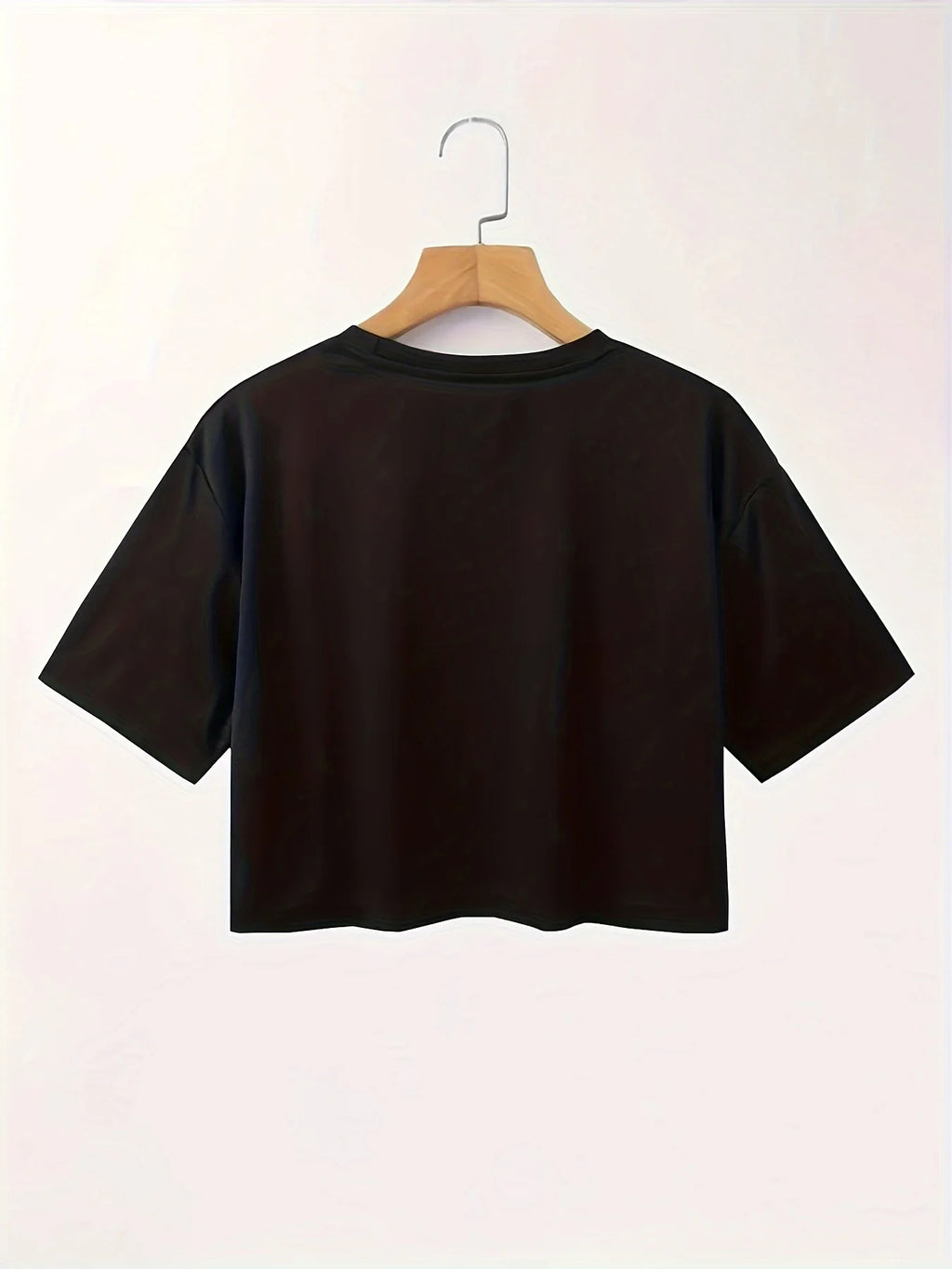 Black t-shirt on a wooden hanger against a white background