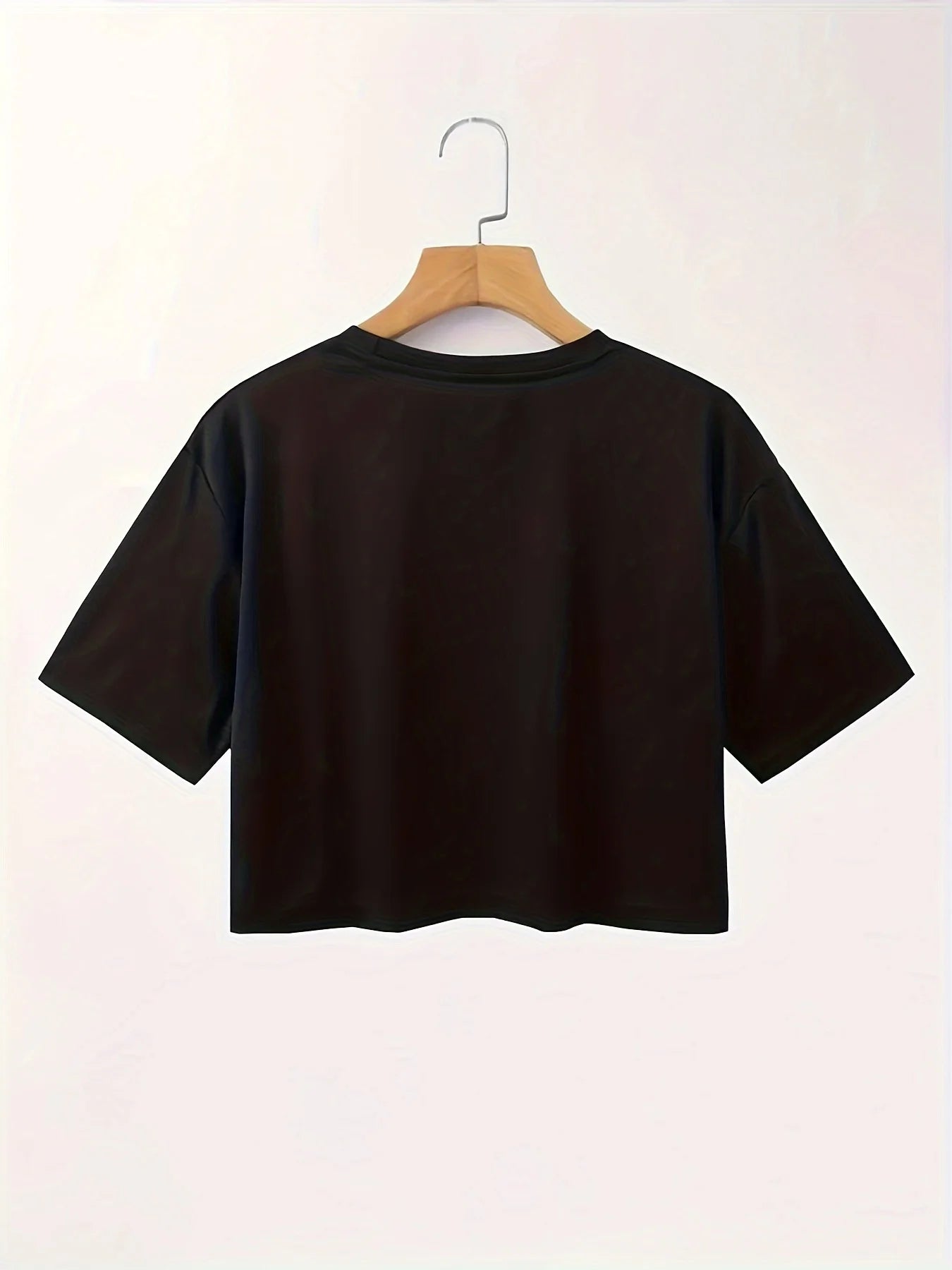 Black t-shirt on a wooden hanger against a white background