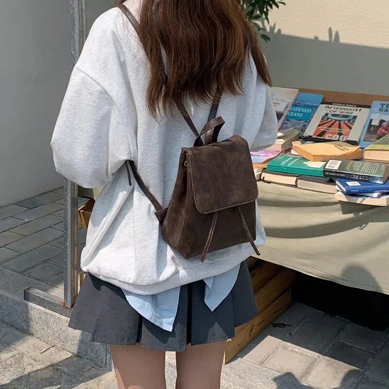 A woman wearing the small drawstring backpack as a shoulder bag.

