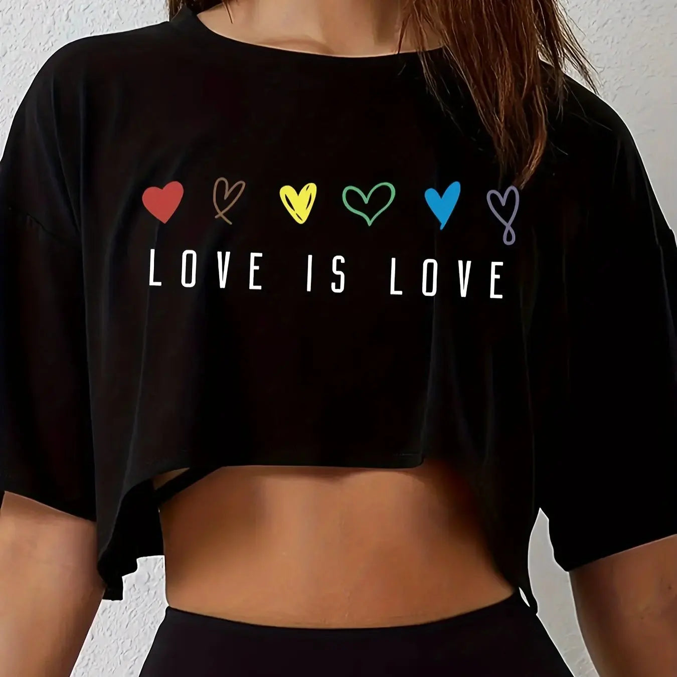 Black crop top with 'LOVE IS LOVE' text and colorful hearts on a plain background
