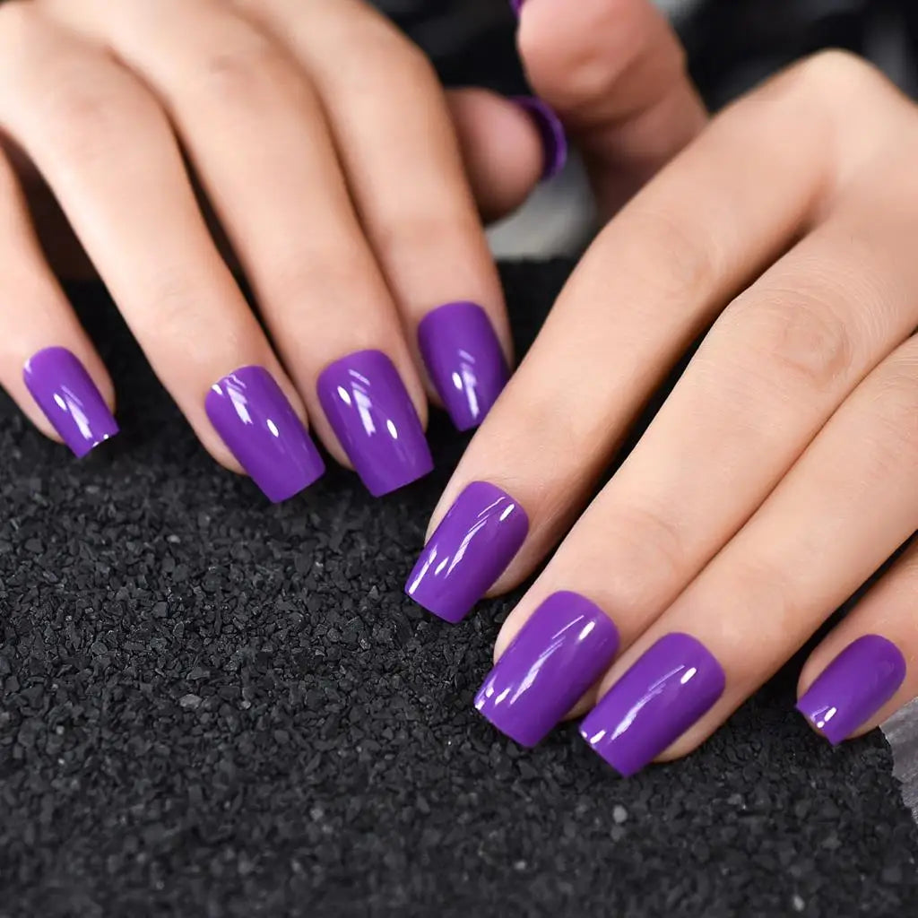 Close-up of hands with purple nail polish on a dark background