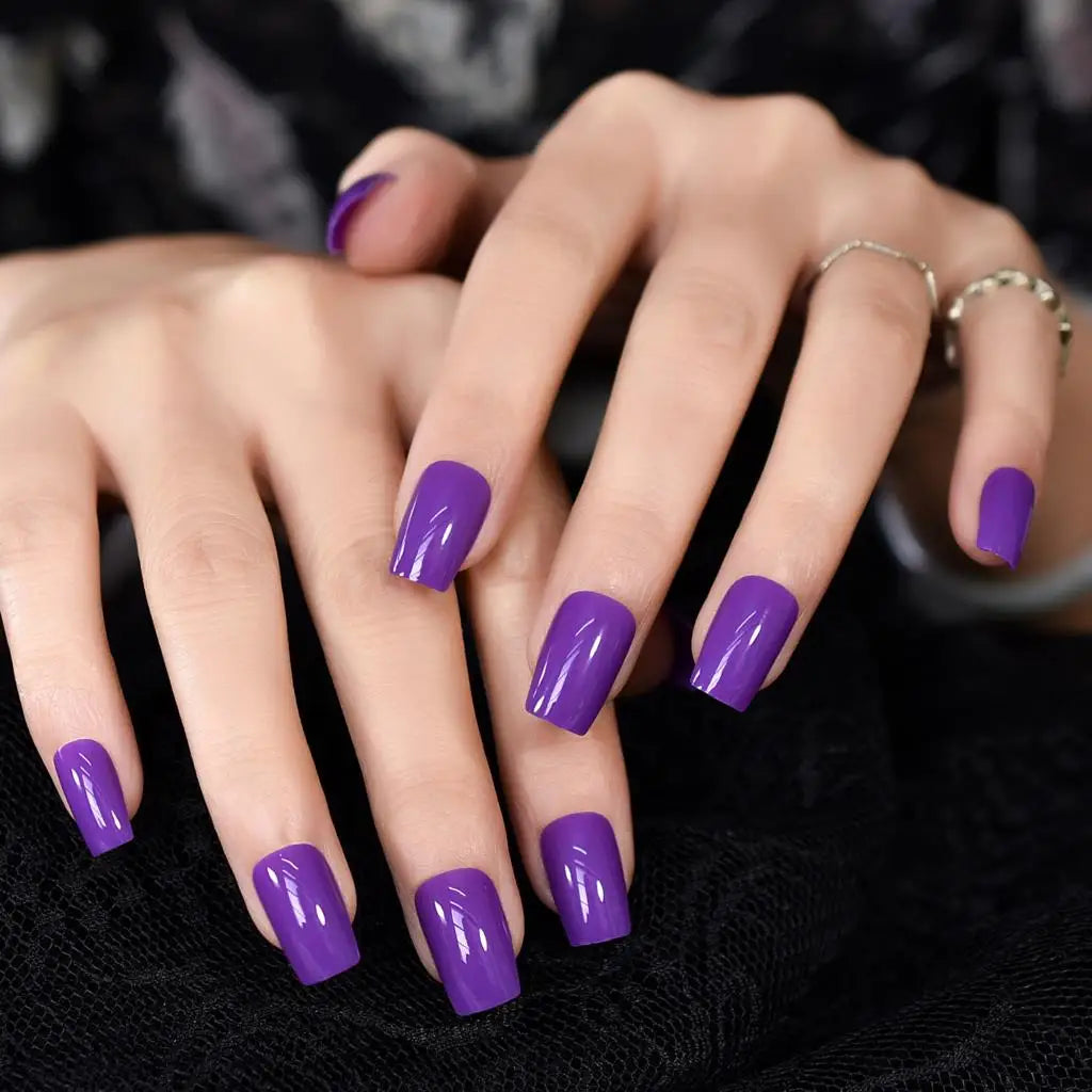Close-up of hands with purple nail polish on a dark background