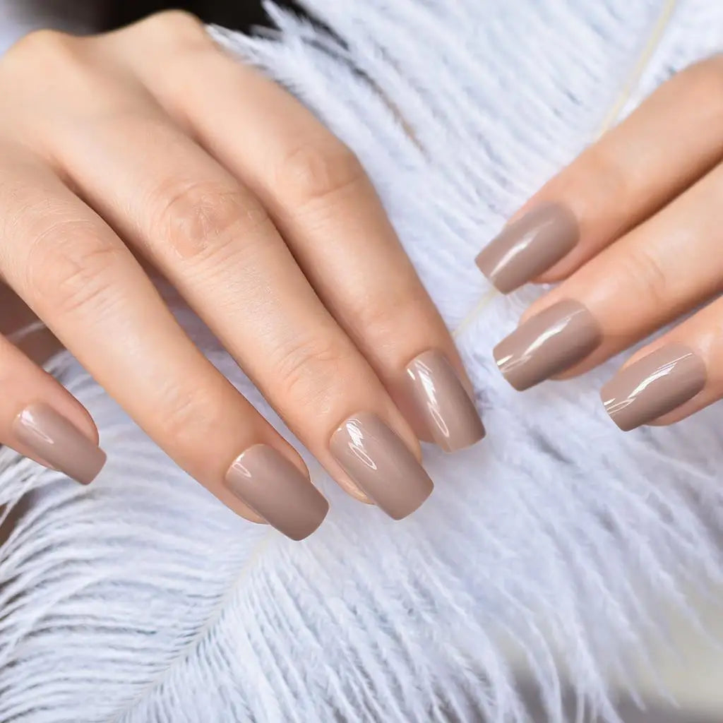 Close-up of hands with beige nail polish on a white feather background