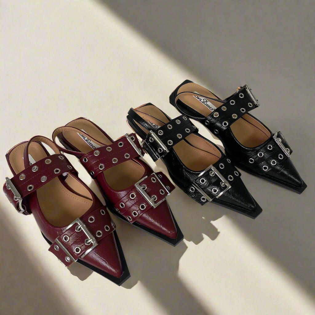 Pair of burgundy and black pointed-toe shoes with buckles on a white background