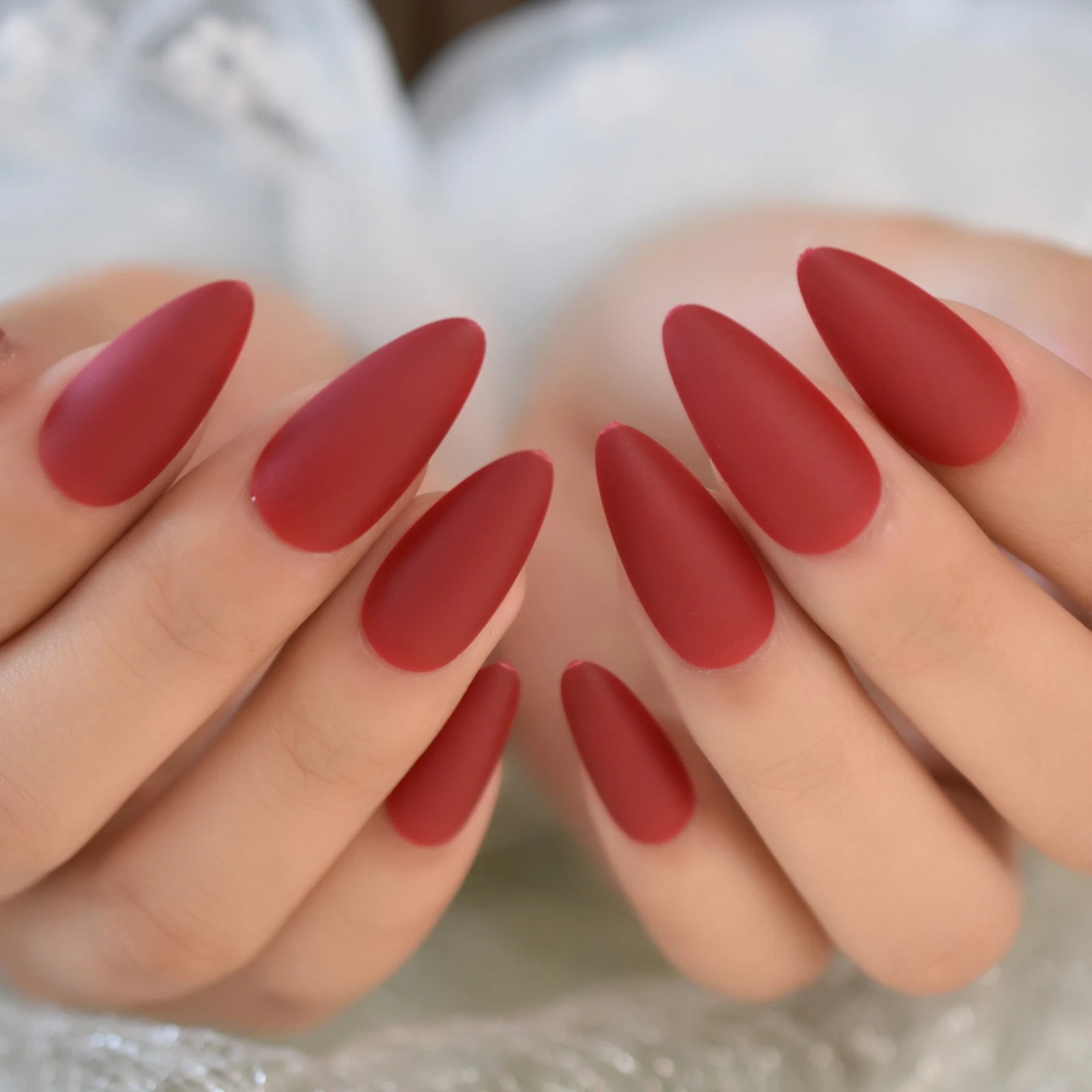 Close-up of hands with red nail polish on a neutral background