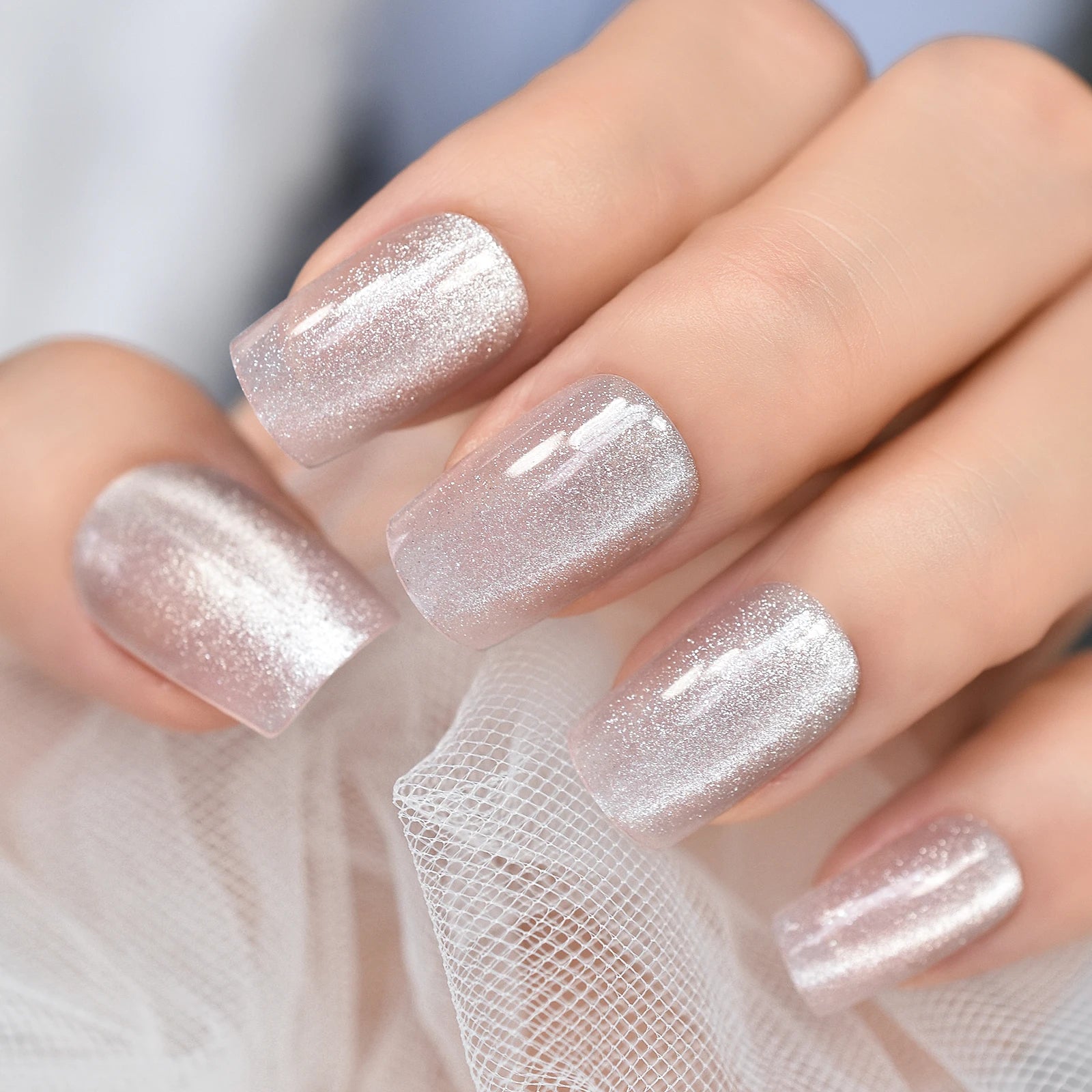 Close-up of a hand with glittery silver nail polish on a blurred background