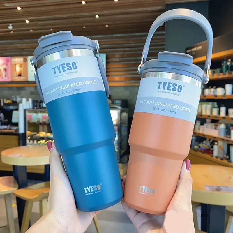A person holding the stainless-steel travel mug, with steam rising from the top.


