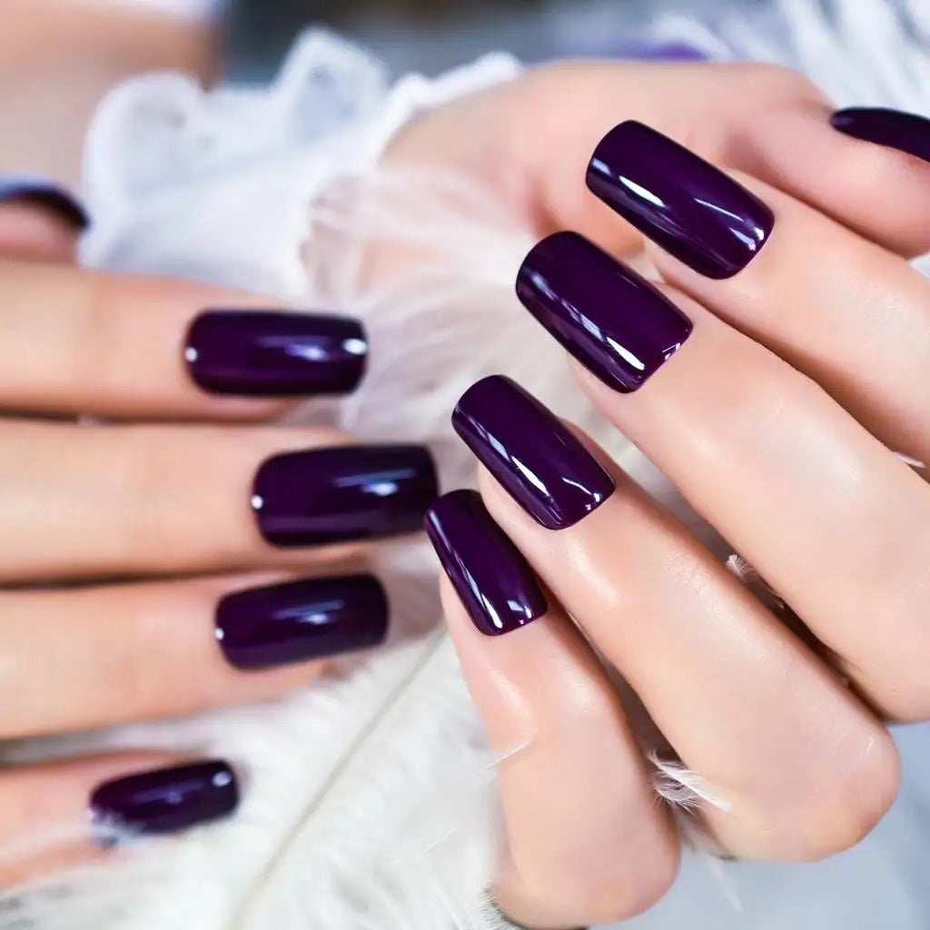 Close-up of hands with dark purple nail polish on a blurred background