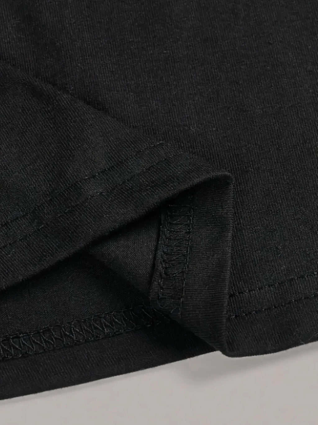 Close-up of a black fabric with visible stitching on a light gray background