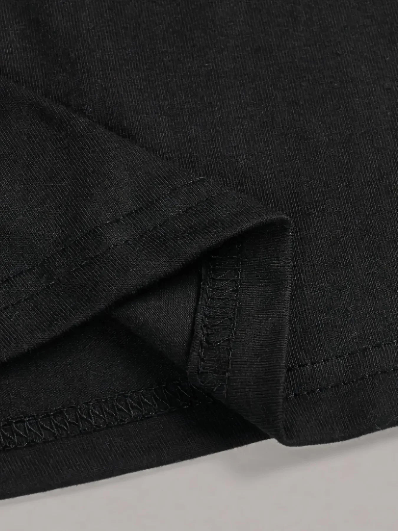 Close-up of a black fabric with visible stitching on a light gray background