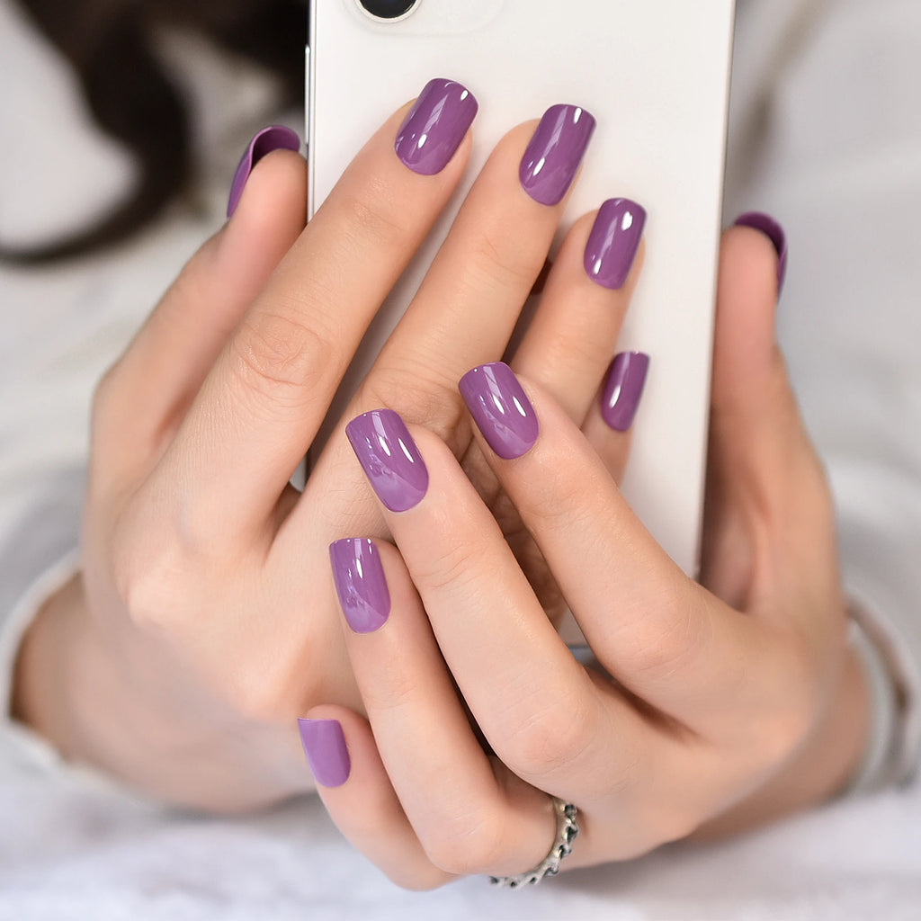 Close-up of hands with purple nail polish holding a phone.