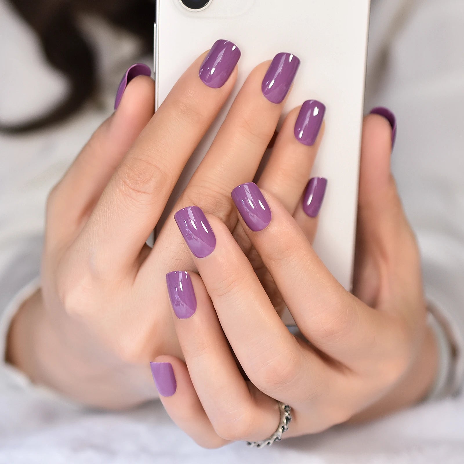 Close-up of hands with purple nail polish holding a phone.