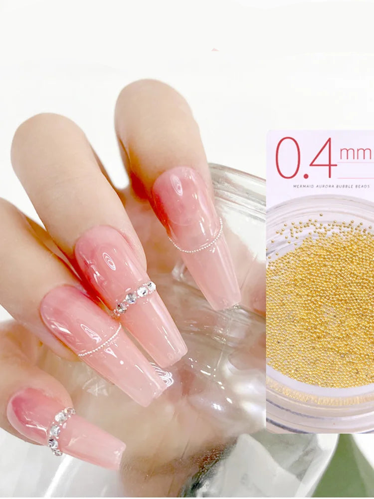 Nail art with clear polish and decorative elements, including a close-up of gold nail steel balls