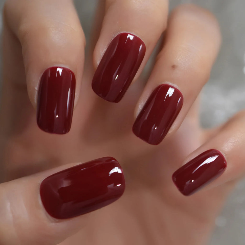 Close-up of a hand with dark red nail polish on a neutral background